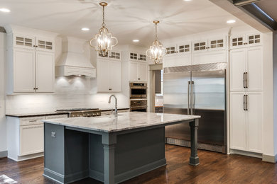 Inspiration for a large timeless l-shaped medium tone wood floor open concept kitchen remodel in Nashville with a farmhouse sink, recessed-panel cabinets, white cabinets, granite countertops, white backsplash, subway tile backsplash, stainless steel appliances and an island