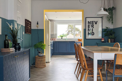 This is an example of a large nautical l-shaped open plan kitchen in Other with an integrated sink, shaker cabinets, blue cabinets, laminate countertops, grey splashback, ceramic splashback, black appliances, laminate floors, an island and grey worktops.