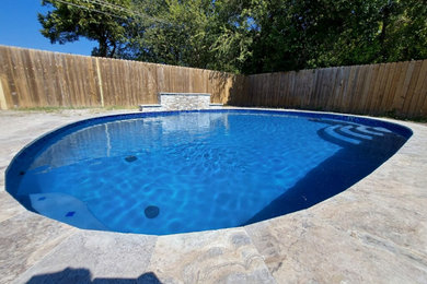Ejemplo de piscina natural actual de tamaño medio redondeada en patio trasero con paisajismo de piscina, privacidad y adoquines de piedra natural
