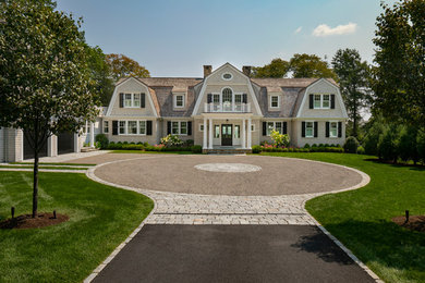 Inspiration for an expansive traditional two-storey beige house exterior in Boston with stone veneer, a gambrel roof and a shingle roof.