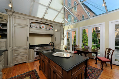 Inspiration for a mid-sized timeless u-shaped medium tone wood floor and brown floor eat-in kitchen remodel in DC Metro with an undermount sink, raised-panel cabinets, beige cabinets, solid surface countertops, red backsplash, brick backsplash, stainless steel appliances and an island