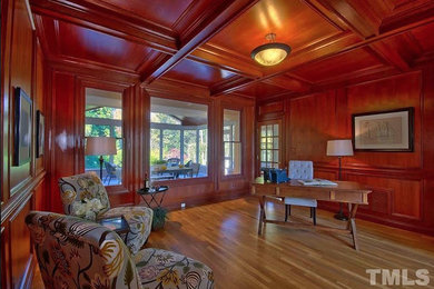 Elegant freestanding desk light wood floor and beige floor home office photo in Raleigh with brown walls