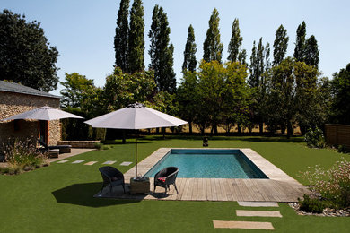 Inspiration for a mid-sized transitional backyard rectangular lap pool in Angers with decking.