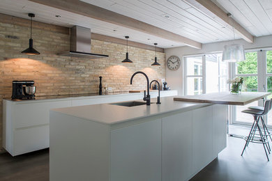 Photo of a large contemporary galley open plan kitchen in Esbjerg with an undermount sink, flat-panel cabinets, white cabinets, stainless steel benchtops, concrete floors, with island and grey floor.