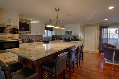 Eat-in kitchen - huge transitional galley medium tone wood floor eat-in kitchen idea in Detroit with an undermount sink, flat-panel cabinets, light wood cabinets, granite countertops, gray backsplash, subway tile backsplash, stainless steel appliances and an island