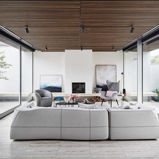 Photo of a modern open concept family room in Melbourne with white walls, a standard fireplace, a plaster fireplace surround and grey floor.