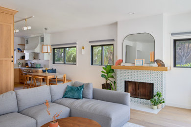 Small trendy open concept light wood floor and brown floor living room photo with white walls, a standard fireplace and a tile fireplace