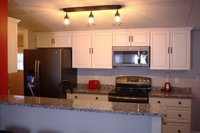 Inspiration for a mid-sized timeless galley kitchen remodel in Miami with an undermount sink, raised-panel cabinets, white cabinets, granite countertops, stainless steel appliances and a peninsula