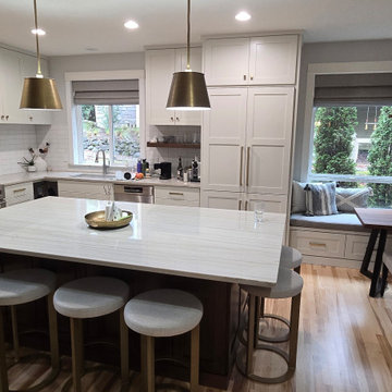 Two-tone kitchen with white shaker style cabinets and walnut island