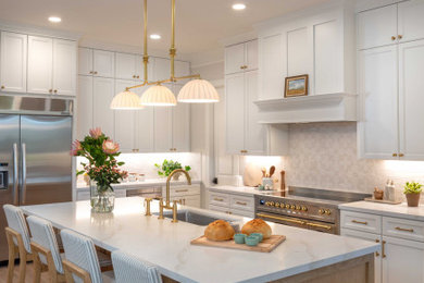 Inspiration for a transitional l-shaped medium tone wood floor and brown floor kitchen remodel in Houston with an undermount sink, shaker cabinets, white cabinets, white backsplash, stainless steel appliances, an island and white countertops
