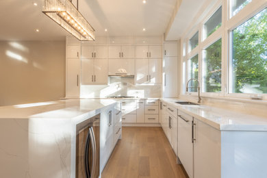 Inspiration for a large contemporary u-shaped light wood floor and beige floor eat-in kitchen remodel in Toronto with an undermount sink, flat-panel cabinets, white cabinets, white backsplash, marble backsplash, stainless steel appliances, an island, white countertops and quartz countertops