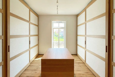 Großes, Neutrales Modernes Ankleidezimmer mit Ankleidebereich, offenen Schränken, hellbraunen Holzschränken, braunem Holzboden und braunem Boden in Hannover