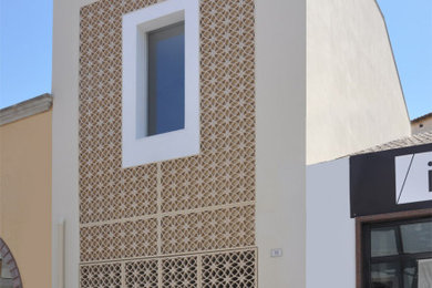 Immagine della facciata di una casa beige contemporanea con rivestimento in cemento, tetto a capanna e copertura in tegole