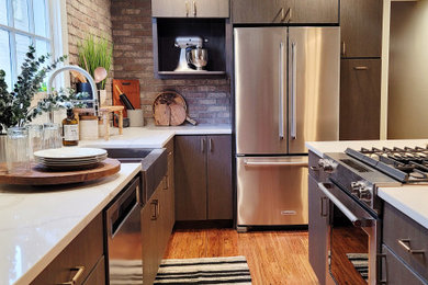Eat-in kitchen - mid-sized industrial l-shaped bamboo floor and brown floor eat-in kitchen idea in New Orleans with a farmhouse sink, flat-panel cabinets, brown cabinets, quartzite countertops, brown backsplash, brick backsplash, stainless steel appliances, an island and white countertops