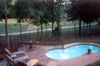 Mid-sized traditional backyard custom-shaped pool in Other with stamped concrete.