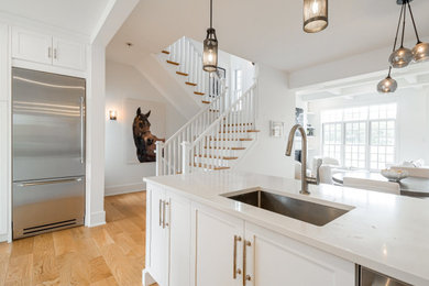 Inspiration for a mid-sized coastal u-shaped light wood floor, brown floor and coffered ceiling eat-in kitchen remodel in Philadelphia with an undermount sink, shaker cabinets, white cabinets, quartz countertops, white backsplash, subway tile backsplash, stainless steel appliances, an island and white countertops