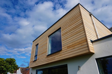 This is an example of a large and white contemporary two floor semi-detached house in Other with wood cladding, a flat roof and a mixed material roof.