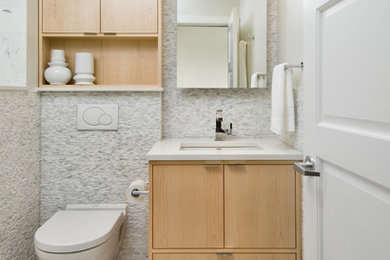Example of a small trendy white tile and stone tile porcelain tile bathroom design in Ottawa with an undermount sink, flat-panel cabinets, light wood cabinets, quartz countertops, a wall-mount toilet and gray walls