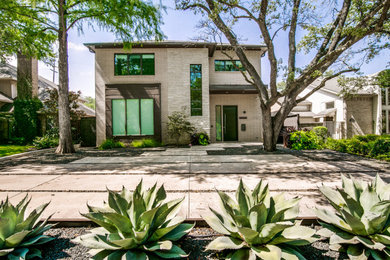 Inspiration for a large contemporary beige two-story brick house exterior remodel in Dallas