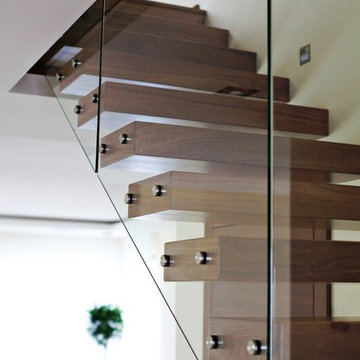 Kragarmtreppe mit Glasgeländer und Holzhandlauf