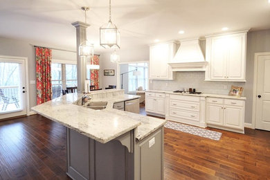 Inspiration for a mid-sized transitional l-shaped medium tone wood floor and brown floor open concept kitchen remodel in Louisville with a double-bowl sink, raised-panel cabinets, white cabinets, granite countertops, white backsplash, porcelain backsplash, stainless steel appliances, an island and white countertops