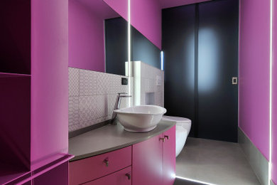 Diseño de aseo flotante actual pequeño con sanitario de dos piezas, paredes rosas, lavabo sobreencimera, suelo gris y encimeras grises