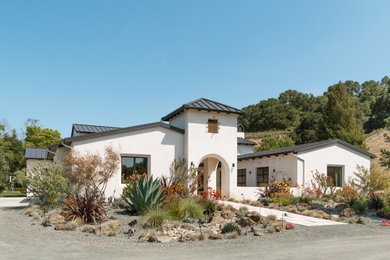 Example of a huge tuscan white one-story stucco exterior home design in San Luis Obispo with a metal roof and a black roof