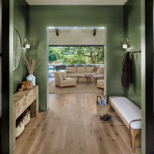 サンフランシスコの両開きドアカントリー風おしゃれな玄関ラウンジ (緑の壁、淡色無垢フローリング、黒いドア、ベージュの床) の写真