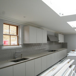 Diseño de cocina de galera, minimalista, grande, cerrada, con fregadero bajoencimera, armarios con paneles lisos, puertas de armario grises, encimera de cuarzo compacto, salpicadero verde, salpicadero de azulejos de cerámica, electrodomésticos de acero inoxidable, suelo de baldosas de porcelana, dos o más islas y encimeras rosas