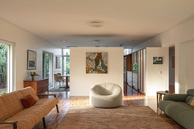 Photo of a mid-sized midcentury living room in Brisbane with medium hardwood floors, no fireplace, multi-coloured floor and brick walls.