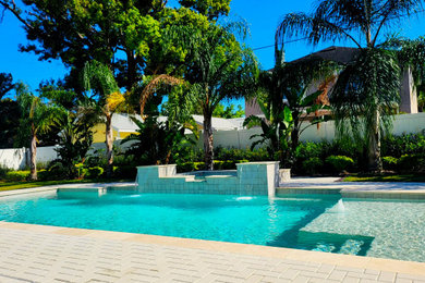 Ejemplo de piscinas y jacuzzis alargados tradicionales renovados rectangulares en patio trasero con adoquines de ladrillo