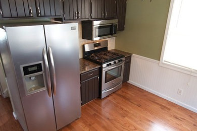 Enclosed kitchen - mid-sized traditional galley light wood floor enclosed kitchen idea in New York with a double-bowl sink, shaker cabinets, dark wood cabinets, granite countertops, beige backsplash, ceramic backsplash, stainless steel appliances and no island