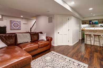 Mid-sized traditional fully buried basement in Columbus with white walls, medium hardwood floors, no fireplace and brown floor.