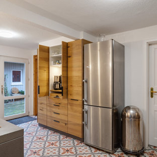 Mid-sized scandinavian galley open plan kitchen in Hamburg with an undermount sink, flat-panel cabinets, medium wood cabinets, concrete benchtops, white splashback, glass sheet splashback, stainless steel appliances, porcelain floors, no island and wallpaper.