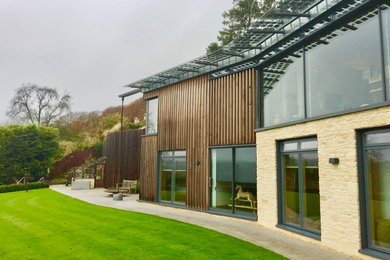 Photo of a large eclectic two floor house exterior in Other with mixed cladding and a flat roof.