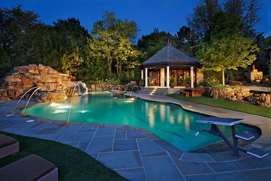 Expansive backyard custom-shaped natural pool in Chicago with a water feature and natural stone pavers.