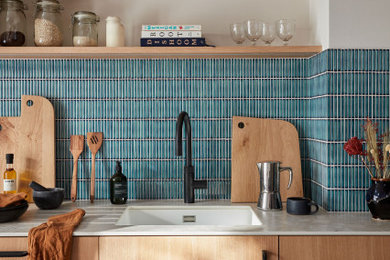 ロンドンにあるモダンスタイルのおしゃれなキッチン (ドロップインシンク、フラットパネル扉のキャビネット、淡色木目調キャビネット、人工大理石カウンター、青いキッチンパネル、セラミックタイルのキッチンパネル、セメントタイルの床、ベージュのキッチンカウンター) の写真