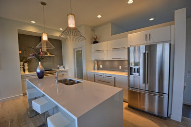 Enclosed kitchen - large l-shaped enclosed kitchen idea in Other with a double-bowl sink, flat-panel cabinets, white cabinets, quartzite countertops, gray backsplash, glass tile backsplash, stainless steel appliances and an island