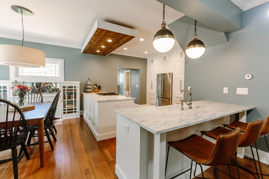 Eat-in kitchen - mid-sized craftsman u-shaped dark wood floor eat-in kitchen idea in Denver with a farmhouse sink, shaker cabinets, white cabinets, solid surface countertops and stainless steel appliances
