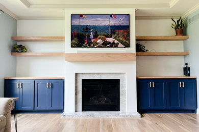 Inspiration for a mid-sized coastal open concept light wood floor, white floor and tray ceiling living room remodel in Kansas City with a bar, blue walls, a wood stove, a stone fireplace and a wall-mounted tv