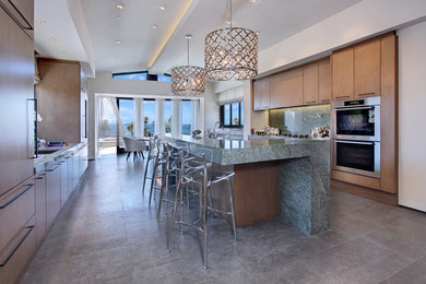 Large beach style galley eat-in kitchen in Los Angeles with stainless steel appliances, light wood cabinets, grey splashback and with island.