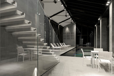 Design ideas for a mid-sized contemporary indoor rectangular infinity pool in Other with natural stone pavers.