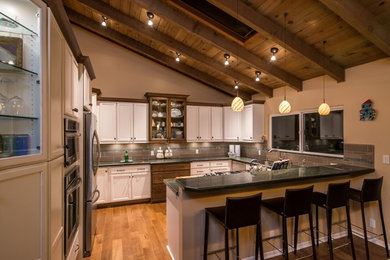 Inspiration for a mid-sized modern u-shaped medium tone wood floor eat-in kitchen remodel in San Diego with a double-bowl sink, recessed-panel cabinets, white cabinets, granite countertops, gray backsplash, stone tile backsplash and stainless steel appliances