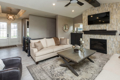 Inspiration for a mid-sized transitional open concept light wood floor and gray floor living room remodel in Other with gray walls, a standard fireplace, a stone fireplace and a wall-mounted tv