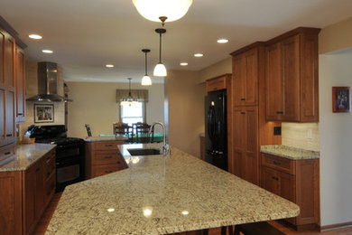 Inspiration for a large transitional l-shaped eat-in kitchen remodel in Milwaukee with shaker cabinets, light wood cabinets, granite countertops, an island, a double-bowl sink, beige backsplash, stone tile backsplash and black appliances