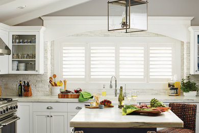 Example of a transitional kitchen design in Orange County with shaker cabinets, white cabinets, marble countertops, white backsplash, stone tile backsplash, stainless steel appliances and an island