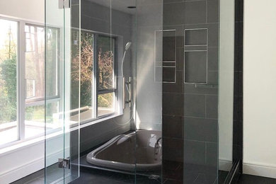 Photo of a large modern master bathroom in Vancouver with flat-panel cabinets, white cabinets, a bidet, black tile, porcelain tile, white walls, porcelain floors, an integrated sink, black floor and a hinged shower door.