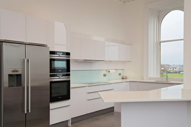 Small modern u-shaped kitchen in Other with flat-panel cabinets, white cabinets, quartz worktops, white splashback, stainless steel appliances and white worktops.