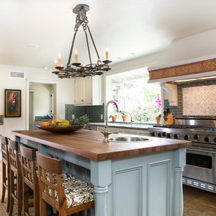 Design ideas for a mid-sized mediterranean kitchen pantry in Los Angeles with a drop-in sink, shaker cabinets, white cabinets, granite benchtops, blue splashback, ceramic splashback, stainless steel appliances, terra-cotta floors and with island.
