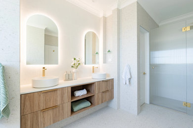 Expansive beach style master bathroom in Sydney with flat-panel cabinets, light wood cabinets, a freestanding tub, an alcove shower, a two-piece toilet, white tile, a vessel sink, solid surface benchtops, multi-coloured floor, a hinged shower door, white benchtops, an enclosed toilet, a double vanity and a floating vanity.